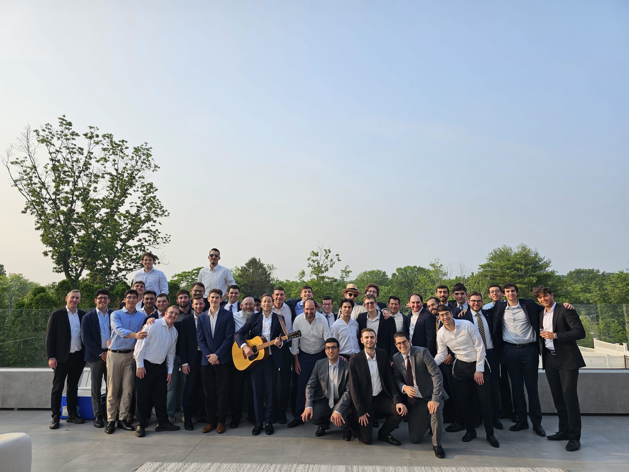 Summer Lakewood Fellowship group photo on a rooftop with a guitar at sunset