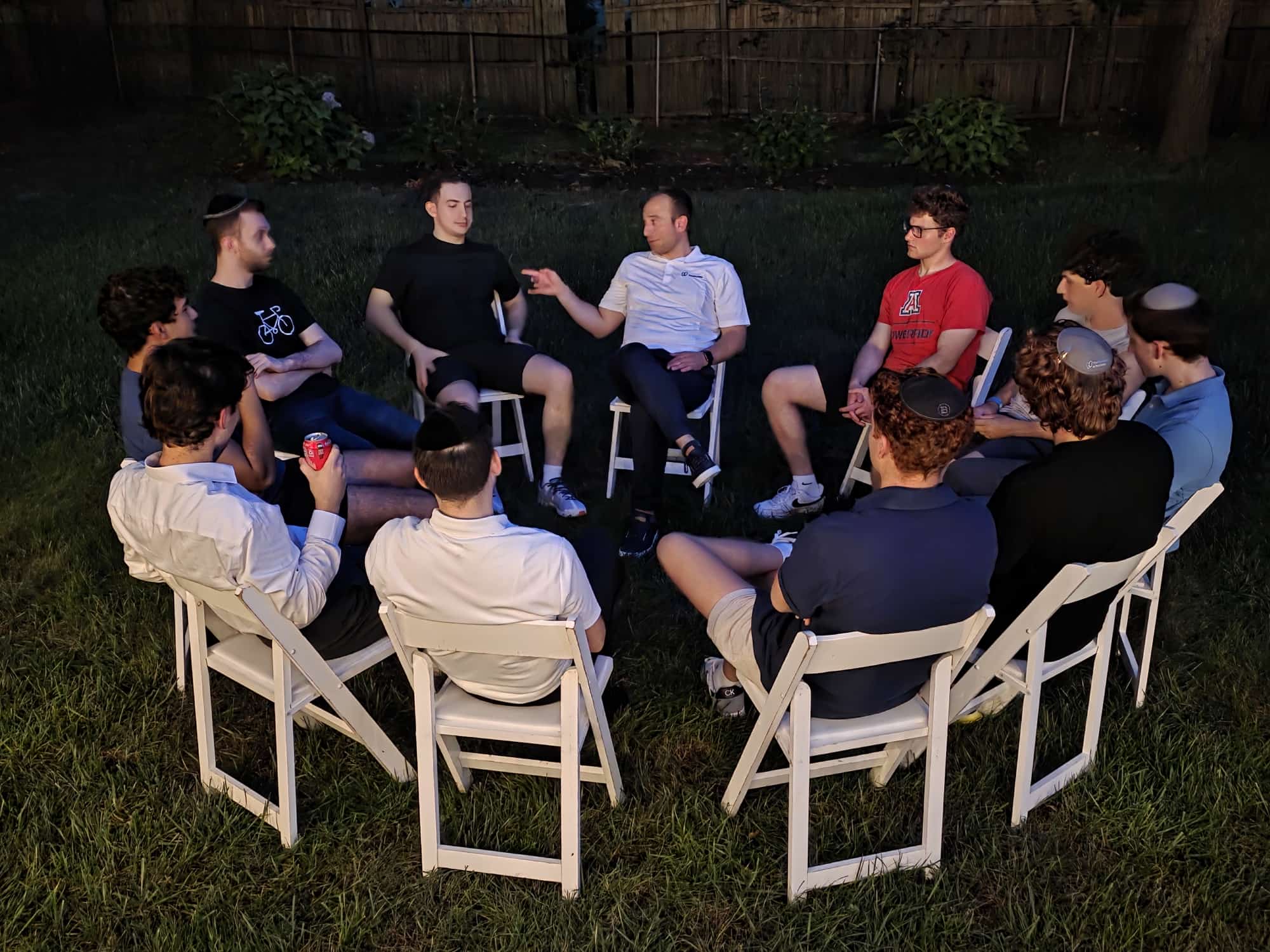 A backyard circle of students in deep conversation at twilight
