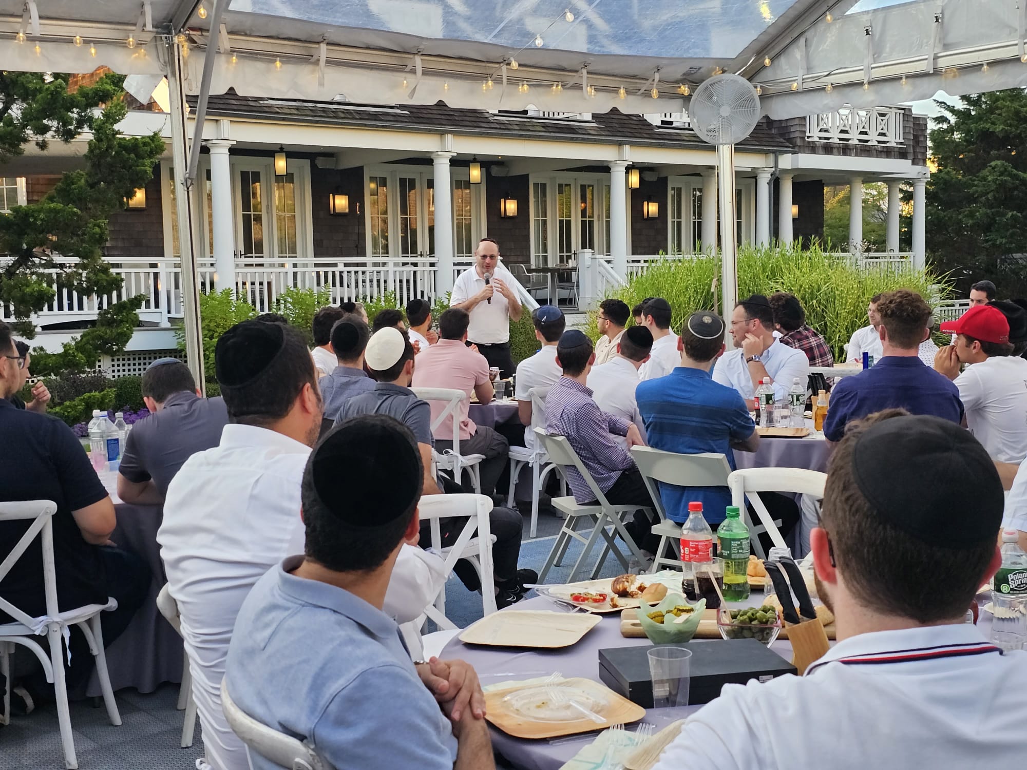Outdoor tent dinner with a rabbi addressing students at the Summer Fellowship